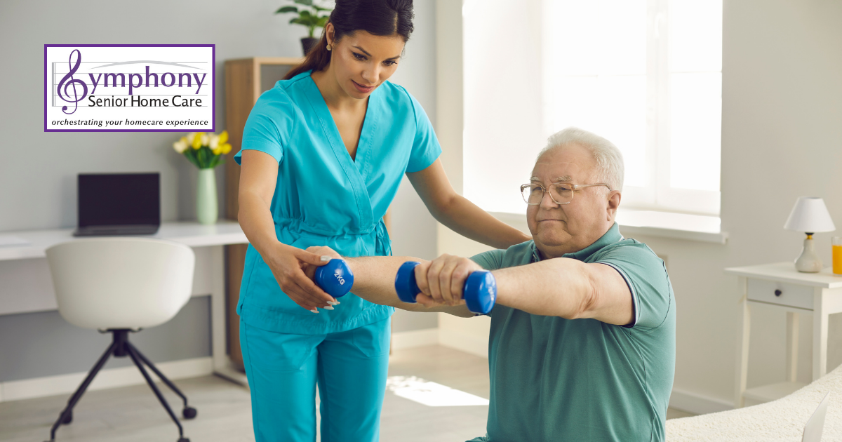 A dedicated in-home caregiver assists a senior in lifting weights as part of a physical therapy routine in a home office-style bedroom.