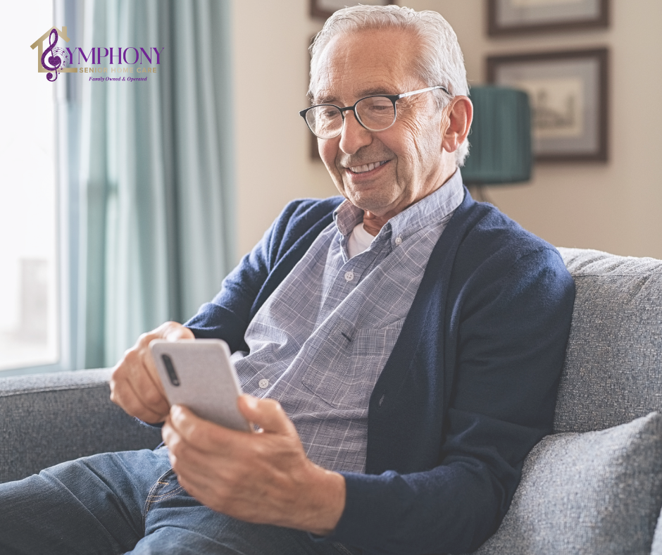 Senior man sitting comfortably at home using his phone, representing common questions about whether it is safe for seniors to live alone.