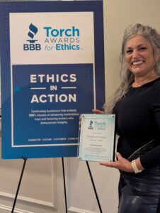Angie Wold of Symphony Senior Home Care in White Bear Lake holding BBB Torch Award Finalist plaque