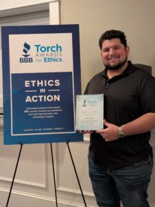 Dimitri from Symphony Senior Home Care holding BBB Torch Award Finalist recognition