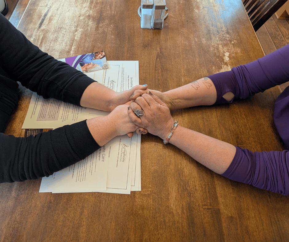 Caregiver and senior client holding hands during an in-home care consultation in White Bear Lake MN